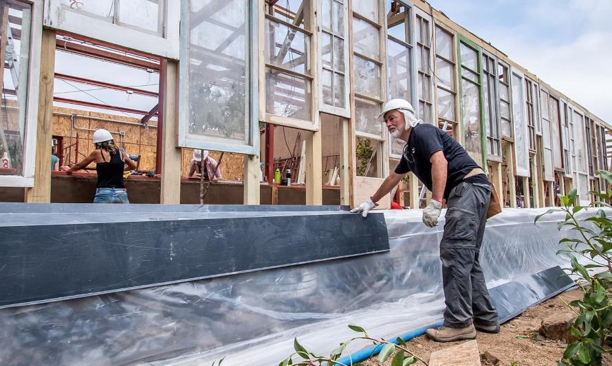 En esta imagen hay un grupo de trabajadoras y trabajadores construyendo una edificación sustentable con vidrio y madera